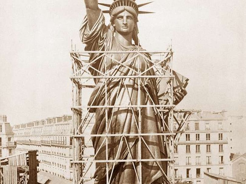 Historic photograph of the Statue of Liberty under construction in Paris, surrounded by scaffolding before its completion and shipment to New York.