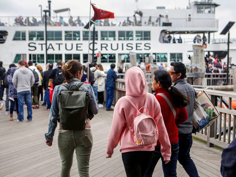 Visitors walking toward a Statue Cruises ferry at the dock during a trip to the Statue of Liberty and Ellis Island.