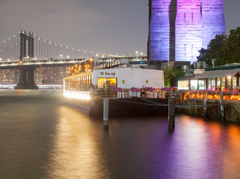 Waterfront restaurant with the Manhattan Bridge illuminated at night