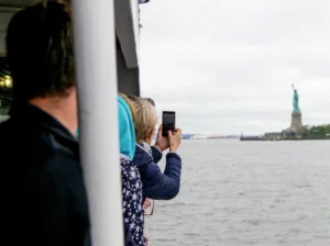 tourists on statue of liberty tour taking photos of the monument