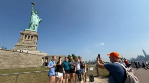 Tour guide taking photos of guests in front of Statue of Liberty monument